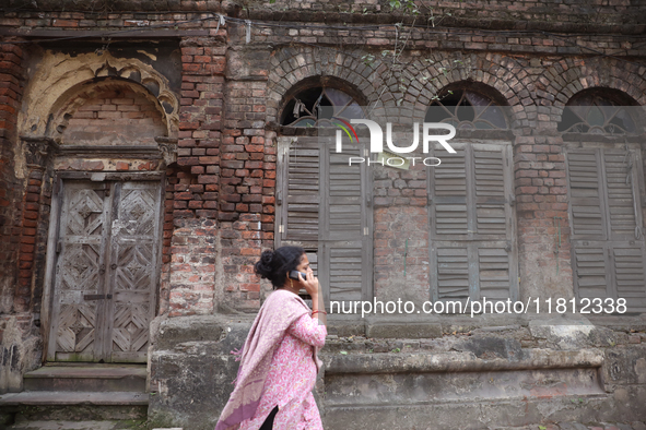 A woman speaks on her mobile phone as she walks past an abandoned temple near a steel and iron wholesale market in Kolkata, India, on Novemb...