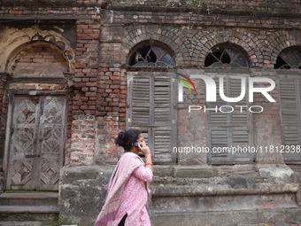 A woman speaks on her mobile phone as she walks past an abandoned temple near a steel and iron wholesale market in Kolkata, India, on Novemb...