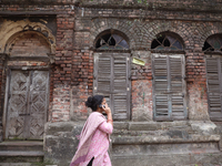 A woman speaks on her mobile phone as she walks past an abandoned temple near a steel and iron wholesale market in Kolkata, India, on Novemb...