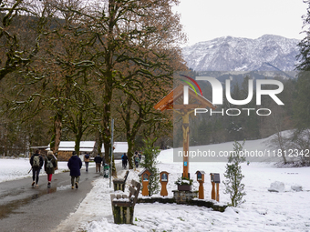 A snow-covered pathway and wooden crucifix create a serene scene in Garmisch-Partenkirchen, on november 24, 2024. (