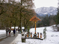 A snow-covered pathway and wooden crucifix create a serene scene in Garmisch-Partenkirchen, on november 24, 2024. (