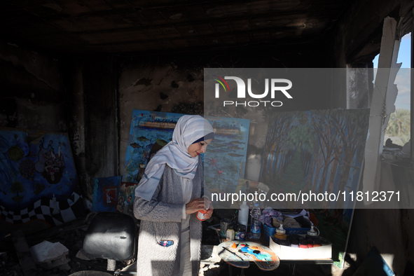 Palestinian artist Maysaa Youssef, 38, paints amidst the rubble of her home, which is destroyed by Israeli shelling in Deir al-Balah, on Nov...