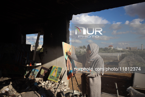 Palestinian artist Maysaa Youssef, 38, paints amidst the rubble of her home, which is destroyed by Israeli shelling in Deir al-Balah, on Nov...