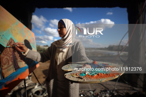 Palestinian artist Maysaa Youssef, 38, paints amidst the rubble of her home, which is destroyed by Israeli shelling in Deir al-Balah, on Nov...