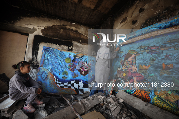 Palestinian artist Maysaa Youssef, 38, paints amidst the rubble of her home, which is destroyed by Israeli shelling in Deir al-Balah, on Nov...