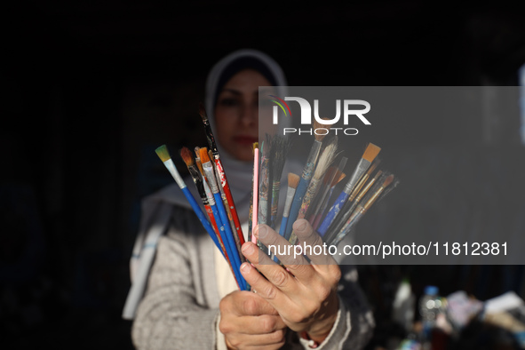 Palestinian artist Maysaa Youssef, 38, paints amidst the rubble of her home, which is destroyed by Israeli shelling in Deir al-Balah, on Nov...