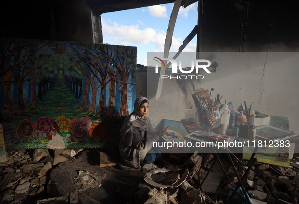 Palestinian artist Maysaa Youssef, 38, paints amidst the rubble of her home, which is destroyed by Israeli shelling in Deir al-Balah, on Nov...