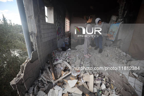 Palestinian artist Maysaa Youssef, 38, paints amidst the rubble of her home, which is destroyed by Israeli shelling in Deir al-Balah, on Nov...