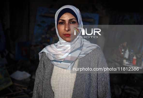 Palestinian artist Maysaa Youssef, 38, paints amidst the rubble of her home, which is destroyed by Israeli shelling in Deir al-Balah, on Nov...