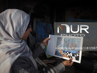 Palestinian artist Maysaa Youssef, 38, paints amidst the rubble of her home, which is destroyed by Israeli shelling in Deir al-Balah, on Nov...