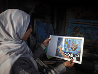 Palestinian artist Maysaa Youssef, 38, paints amidst the rubble of her home, which is destroyed by Israeli shelling in Deir al-Balah, on Nov...