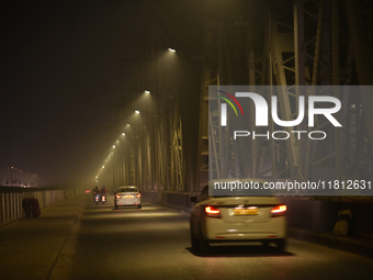 Vehicles travel along the Vivekananda Bridge over the Ganga River on a foggy winter night in Kolkata, India, on November 26, 2024. (