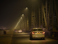 Vehicles travel along the Vivekananda Bridge over the Ganga River on a foggy winter night in Kolkata, India, on November 26, 2024. (