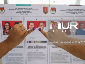 A person shows her inked finger after casting her vote during the simultaneous regional election in Semarang, Central Java Province, on Nove...