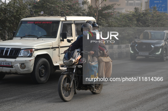 Pillion riders wear face masks as the air pollution crisis continues in New Delhi, India, on November 27, 2024. 