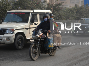 Pillion riders wear face masks as the air pollution crisis continues in New Delhi, India, on November 27, 2024. (