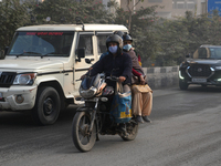 Pillion riders wear face masks as the air pollution crisis continues in New Delhi, India, on November 27, 2024. (