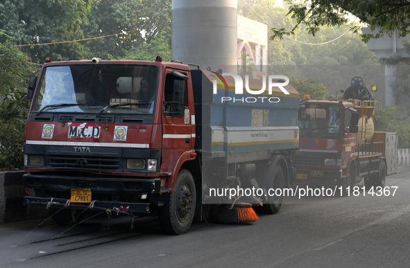 Vehicles belonging to the Municipal Corporation of Delhi sprinkle water on the roadside dust at Jamia Milia Islamia University in New Delhi,...