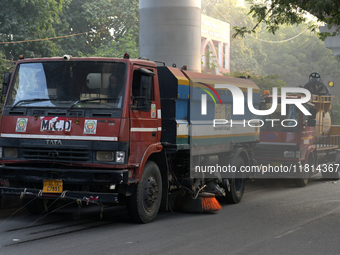 Vehicles belonging to the Municipal Corporation of Delhi sprinkle water on the roadside dust at Jamia Milia Islamia University in New Delhi,...