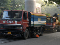 Vehicles belonging to the Municipal Corporation of Delhi sprinkle water on the roadside dust at Jamia Milia Islamia University in New Delhi,...