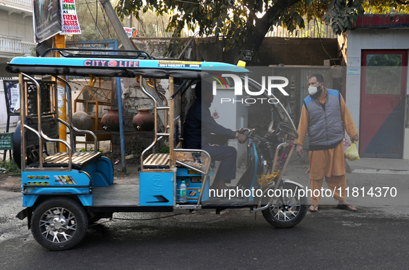 A man wearing a face mask stops an e-rickshaw in New Delhi, India, on November 27, 2024. 