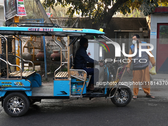 A man wearing a face mask stops an e-rickshaw in New Delhi, India, on November 27, 2024. (