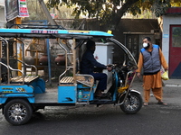 A man wearing a face mask stops an e-rickshaw in New Delhi, India, on November 27, 2024. (