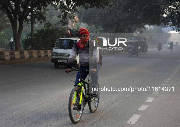 A cyclist covers his head with a scarf as the temperature drops and air pollution levels remain in the ''very poor'' category in New Delhi,...