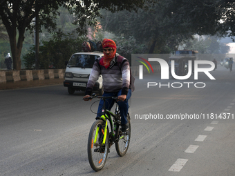 A cyclist covers his head with a scarf as the temperature drops and air pollution levels remain in the ''very poor'' category in New Delhi,...