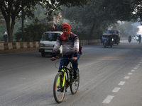 A cyclist covers his head with a scarf as the temperature drops and air pollution levels remain in the ''very poor'' category in New Delhi,...