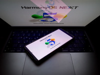 The logo of the Huawei HarmonyOS NEXT operating system appears on a smartphone screen and on a computer screen as a background in this photo...