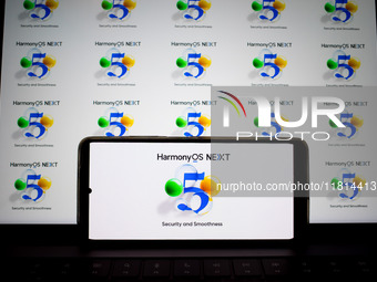 The logo of the Huawei HarmonyOS NEXT operating system appears on a smartphone screen and on a computer screen as a background in this photo...