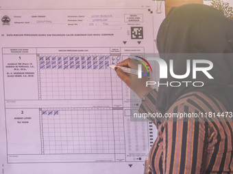 An election staffer counts ballots at a polling station in Semarang, Central Java Province, on November 27, 2024, after Indonesians vote to...