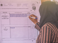 An election staffer counts ballots at a polling station in Semarang, Central Java Province, on November 27, 2024, after Indonesians vote to...