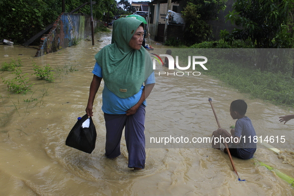 A resident and his children walk in the middle of floodwaters as the intensity of rain increases in Medan City, Indonesia, on November 27, 2...