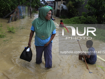 A resident and his children walk in the middle of floodwaters as the intensity of rain increases in Medan City, Indonesia, on November 27, 2...