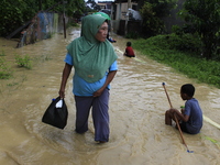 A resident and his children walk in the middle of floodwaters as the intensity of rain increases in Medan City, Indonesia, on November 27, 2...