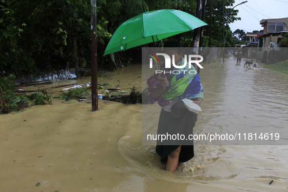 A woman with an umbrella walks in the middle of a flood as the intensity of rainfall increases in Medan, Indonesia, on November 27, 2024. Se...