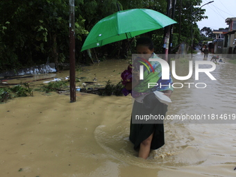 A woman with an umbrella walks in the middle of a flood as the intensity of rainfall increases in Medan, Indonesia, on November 27, 2024. Se...