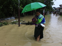 A woman with an umbrella walks in the middle of a flood as the intensity of rainfall increases in Medan, Indonesia, on November 27, 2024. Se...