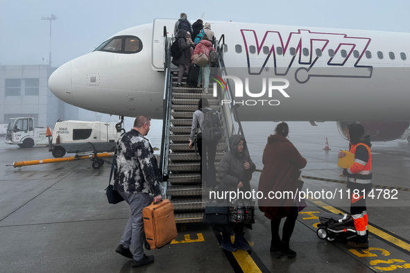 People board Wizz Air plane on the foggy morning at the airport in Balice near Krakow, Poland on November 27, 2024. 