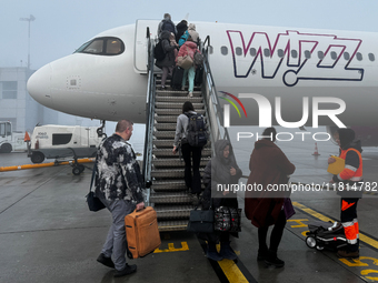 People board Wizz Air plane on the foggy morning at the airport in Balice near Krakow, Poland on November 27, 2024. (