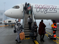 People board Wizz Air plane on the foggy morning at the airport in Balice near Krakow, Poland on November 27, 2024. (