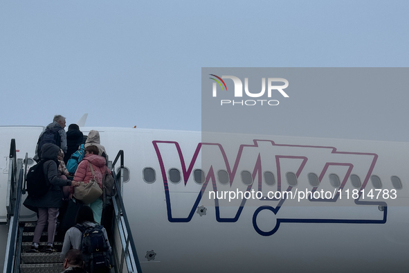 People board Wizz Air plane on the foggy morning at the airport in Balice near Krakow, Poland on November 27, 2024. 