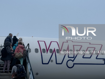 People board Wizz Air plane on the foggy morning at the airport in Balice near Krakow, Poland on November 27, 2024. (