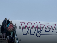 People board Wizz Air plane on the foggy morning at the airport in Balice near Krakow, Poland on November 27, 2024. (