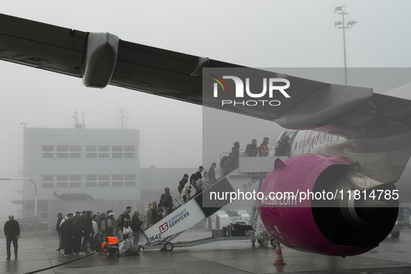 People board Wizz Air plane on the foggy morning at the airport in Balice near Krakow, Poland on November 27, 2024. 