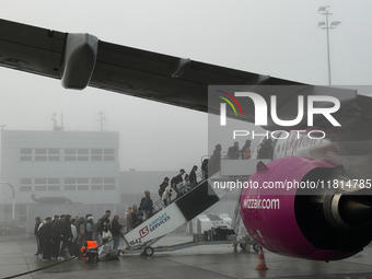 People board Wizz Air plane on the foggy morning at the airport in Balice near Krakow, Poland on November 27, 2024. (