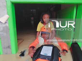 An officer from the Indonesian National SAR Agency carries out rescues for children and residents who are victims of flooding in Medan, Nort...