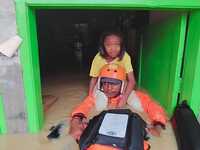 An officer from the Indonesian National SAR Agency carries out rescues for children and residents who are victims of flooding in Medan, Nort...